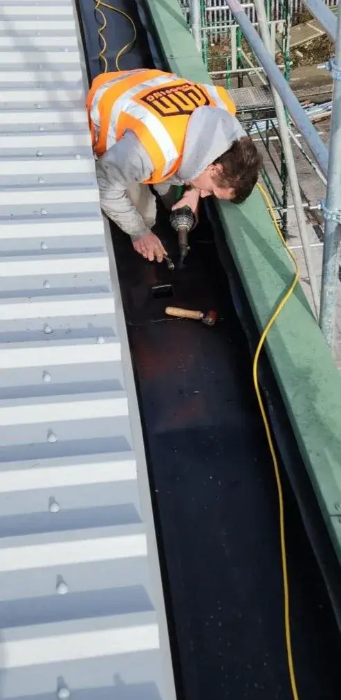 Roofer installing gutter lining by hand